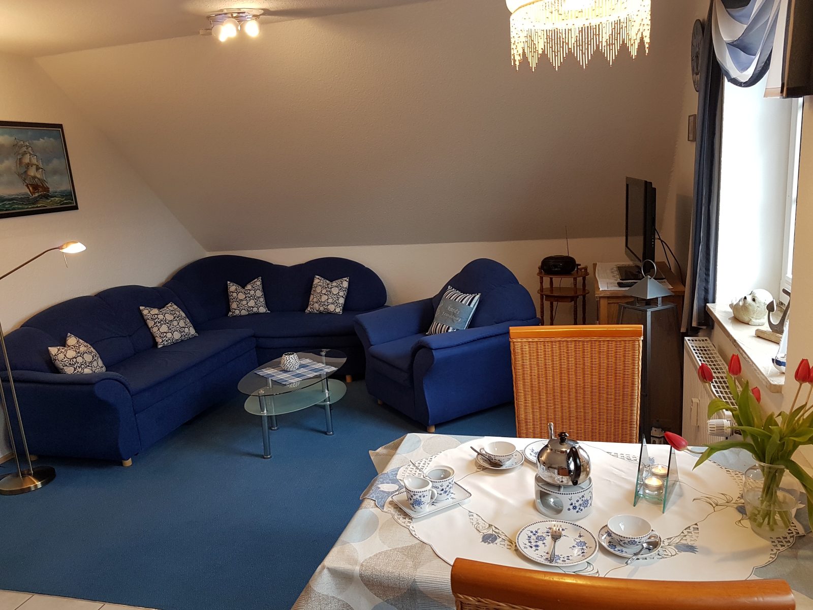 Wohnzimmer mit blauer Couch und gedecktem Tisch in Astrids Ferienwohnung II